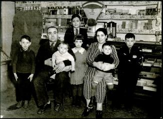 La famille DiLallo pose dans le commerce familial. Il y a le père, la mère et six enfants.