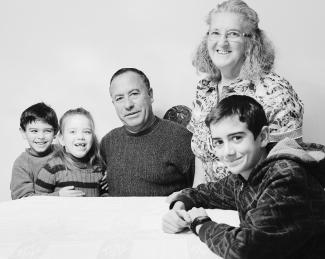 Photo en noir et blanc montrant un grand-père, assis, sa femme à ses côtés, debout, et leurs trois petits-enfants autour d’eux, deux d’un côté et un de l’autre.  