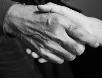 Photo en noir et blanc montrant deux mains qui se serrent en plan rapproché.