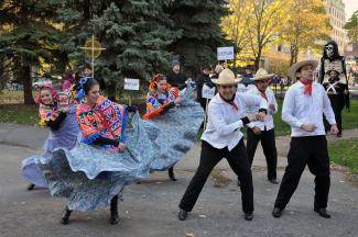 Trois hommes et trois femmes dansent dans un parc en habits traditionnels mexicains