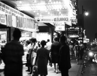 Photographie de la rue Sainte-Catherine éclairée par les enseignes lumineuses, le soir.