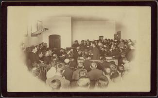 Photographie de Louis Riel, de profil au centre, s'adressant au jury, à gauche.