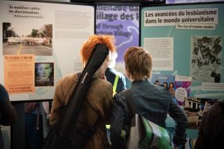 Deux personnes regardent des modules d’exposition dans un espace public.