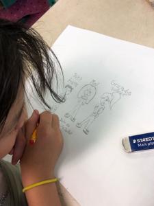 Une jeune fille dessine sa famille sur une feuille.