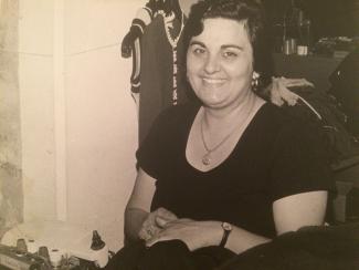 Femme assise et souriante devant une machine à coudre
