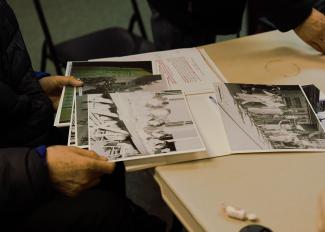 Close-up of a man’s hands, holding photographs from a file.