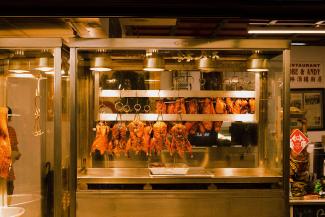 Gros plan sur des poulets barbecue suspendus à la chaleur dans un restaurant.