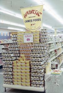 Photo couleur de l'intérieur d'une épicerie avec des produits chinois de marque Ahuntsic sur un étalage.