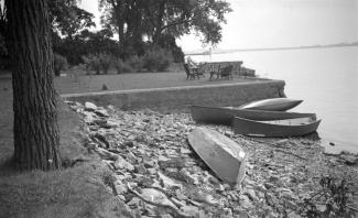 Berges naturelles avec des chaloupes et une terrasse surélevée sur laquelle se trouvent des chaises et une table, à proximité du lac.