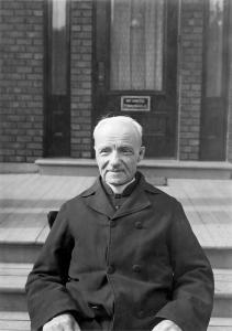 Portrait de frère André devant l’infirmerie provinciale vers 1925.
