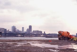 Photo prise de la Cité du Havre en construction montrant un camion orange à l'avant-plan et le Vieux-Montréal à l'arrière-plan