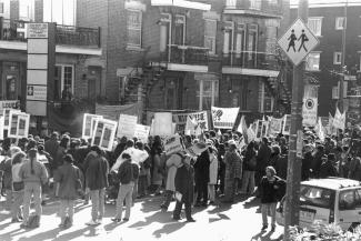 Des dizaines de personnes manifestent dans la rue en tenant des pancartes.