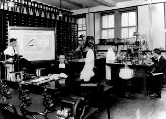 Photographie du frère Marie-Victorin (au centre) et d'hommes dans le laboratoire.