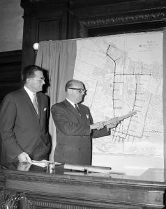 Photographie de Jean Drapeau, accompagné d'un homme, présentant un plan du métro.