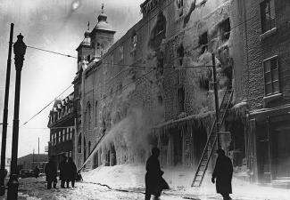 Photographie de pompiers éteignant l'incendie de la cathédrale, dont la façade est endommagée.