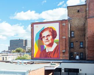 Toits de la ville, avec la murale d’un portrait de femme en couleurs, sur un des murs en briques. 