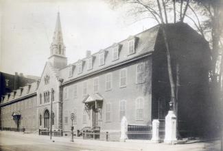 Immeuble ancien, de trois étages, avec clocher, bordant une rue.