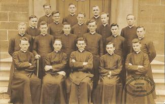 Photographie de groupe des jeunes prêtres posant devant le séminaire à Montréal. Paul-Émile se trouve en avant au centre. 