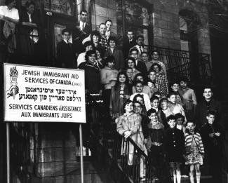 Groupe d'enfants accompagnés d'adultes se tenant dans les escaliers d'un immeuble.