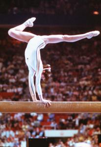 Photographie de Nadia Comaneci en chandelle sur une poutre.