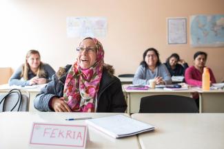 Cinq femmes sont assises à des tables dans une classe. 