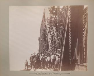 Les hommes qui ont travaillé à la construction du pont posent devant et sur la structure métallique du pont.