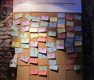 Réflexions des visiteurs sur le Montréal d’hier, d’aujourd’hui et de demain sur de petits cartons colorés sur un tableau de liège.