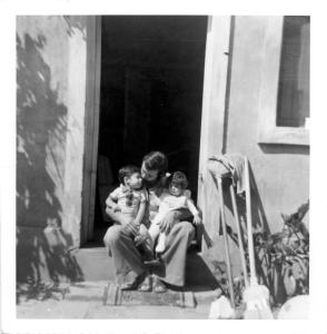 Un père et ses deux jeunes enfants assis sur le pas de la porte de leur maison au Chili