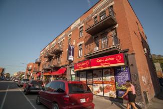 Façade du Sabor Latino. On voit des voitures stationnées et un couple de piétons.