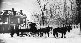 Photographie d'une voiture attelée à des chevaux, en hiver.