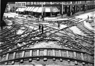 Photographie en plongée d'un croisement de voies de tramway à l'angle de deux rues.