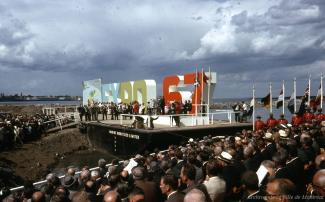 Site de la cérémonie du début de la construction. On voit les lettres Expo 67 et une foule assise.