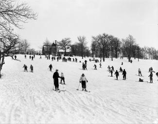 Photographie en contre-plongée de gens descendant une piste enneigée en ski.