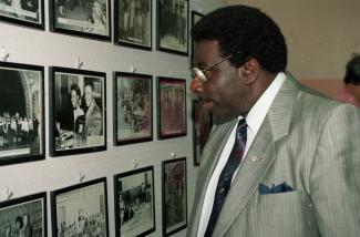 Le pianiste jazz Oliver Jones regardant un mur de photos encadrées au Negro Community Centre