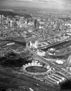 Vue aérienne de l'autoroute Bonaventure parmi le paysage urbain montréalais, vue du sud. On aperçoit l'usine Five Roses au centre ainsi que le mont Royal en haut à gauche.