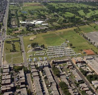 Vue aérienne couleur montrant un parc, des édifices et des rues. 