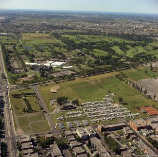 Vue aérienne montrant un grand espace vert dans une ville. 