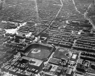 Vue aérienne en noir et blanc montrant un stade de baseball dans une ville densément bâtie.