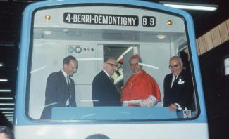 Photographie couleur de quatre messieurs à l'avant du wagon de métro indiquant « 4-BERRI-DEMONTIGNY ». De l'extrême droite à gauche, Lucien L'Allier, Paul-Émile Léger et Jean Drapeau