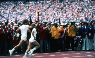 Deux athlètes courent en tenant la flamme olympique à la cérémonie d’ouverture des Jeux olympiques de 1976.