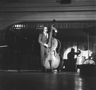 Photographie en noir et blanc d’un homme noir jouant de la contrebasse sur une scène.