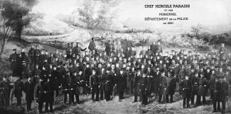 Photographie en noir et blanc d’un groupe de policiers en uniforme. Il y a une inscription dans le coin supérieur droit.