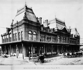 Vue extérieure de la gare avec des voitures tirées par des chevaux