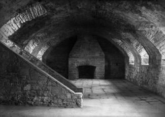 Photographie d'une pièce du fort de l'île Sainte-Hélène. On y voit un escalier en pierre et un foyer.