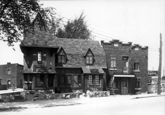 Photo en noir et blanc montrant le restaurant Au lutin et un duplex adjacent au restaurant. 