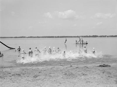 Des enfants se tenant par la main entrent dans l’eau sur une plage