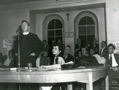 Madeleine Parent, (leader syndical), local 100, grève contre la Montreal Cotton Co. Assemblée du 2 septembre 1946; le révérend Claude de Mestral au micro, Madeleine Parent est assise à côté de lui.