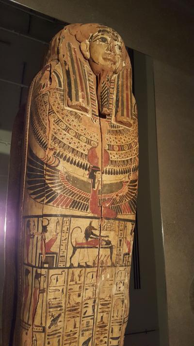 Sarcophage d’Hetep-Bastet présentant une riche décoration sur fond jaune avec de nombreuses divinités peintes, dont Isis aux ailes déployées et Anubis momifiant un corps.