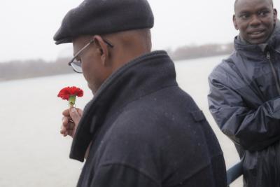 Un Rwandais tient une fleur rouge dans sa main et un autre homme si tient à côté