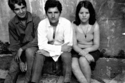 Photo en noir et blanc de trois adolescents dans la cour arrière de la maison familiale. 